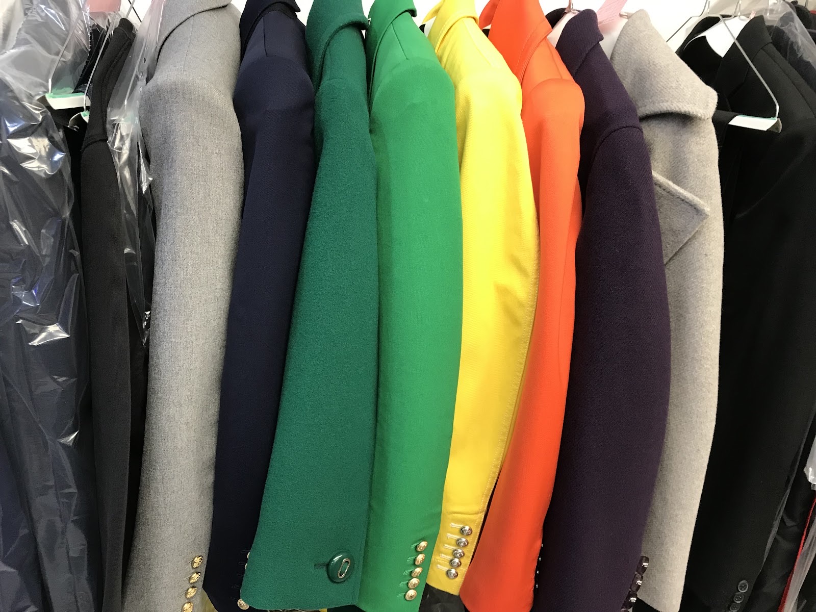 A rail of cleaned coats and jackets in green, yellow, orange, grey and navy