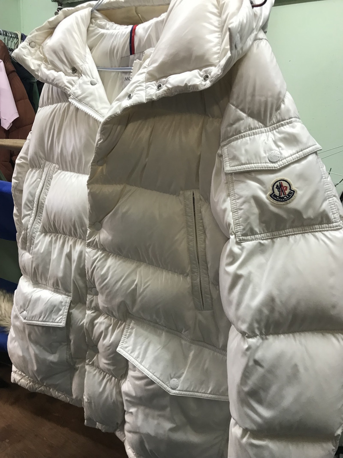 Cream padded down coat hanging in the shop after cleaning